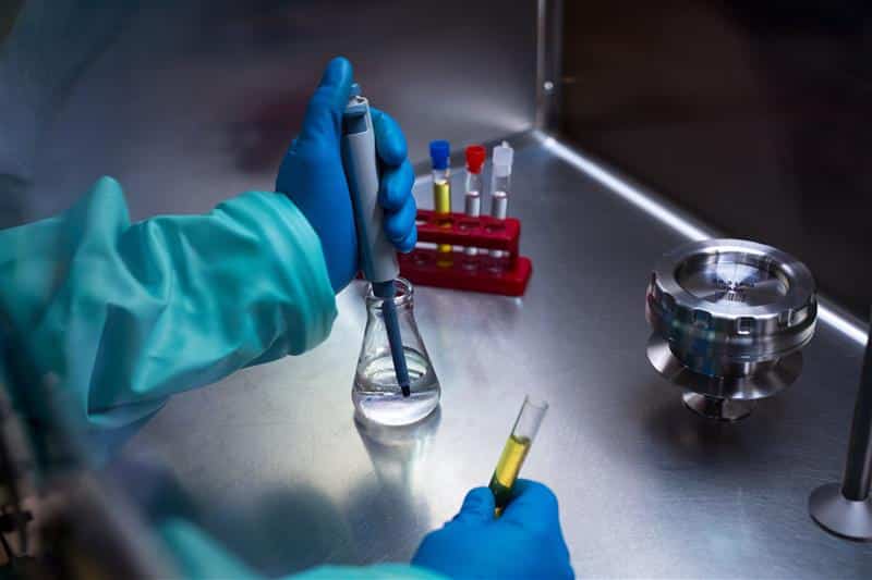 Photographie du personnel de salle blanche en blouse utilisant le ActiveCount Remote Impactor Kit dans une enceinte de sécurité biologique.