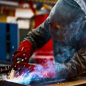 photo d'un soudeur portant un masque de soudage en train de souder un objet métallique avec des étincelles qui jaillissent